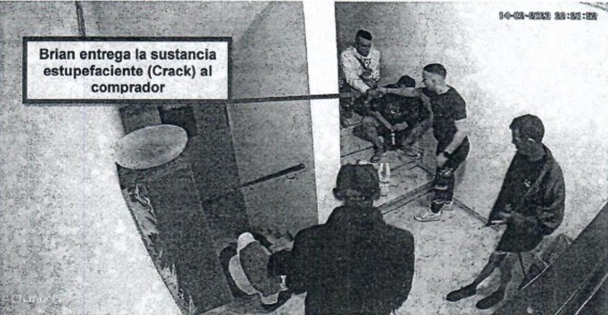 Uno de los acusados, vestido de oscuro y con playeras blancas, realiza una transacción, presuntamente de crack, a uno de sus compradores en el rellano del edificio en el que vive