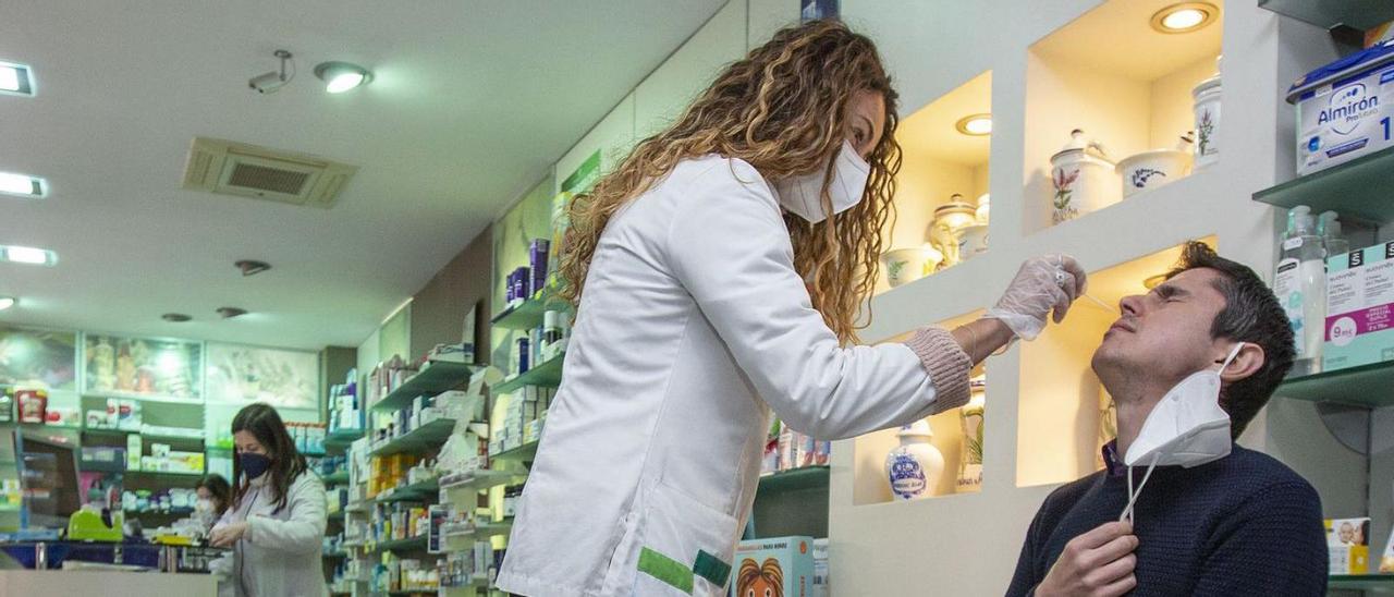 Una farmacéutica toma una muestra a un paciente para un test de antígenos. |