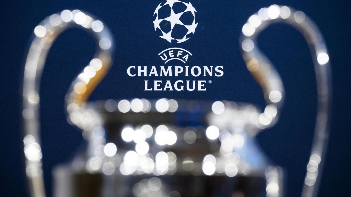 El trofeo de la Champions fotografiado frente a la lona de fondo del sorteo.