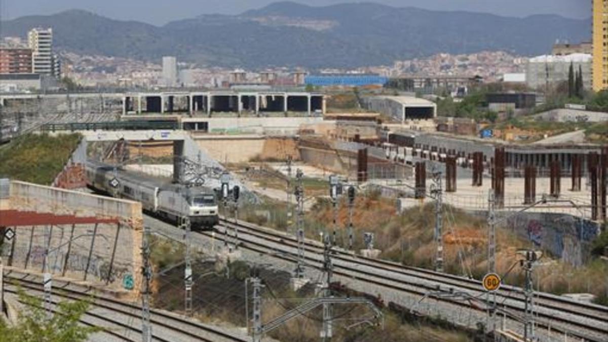Un tren de Regionals de Renfe cruza la enorme extensión de las obras abandonadas de la estación multimodal de La Sagrera, ayer.