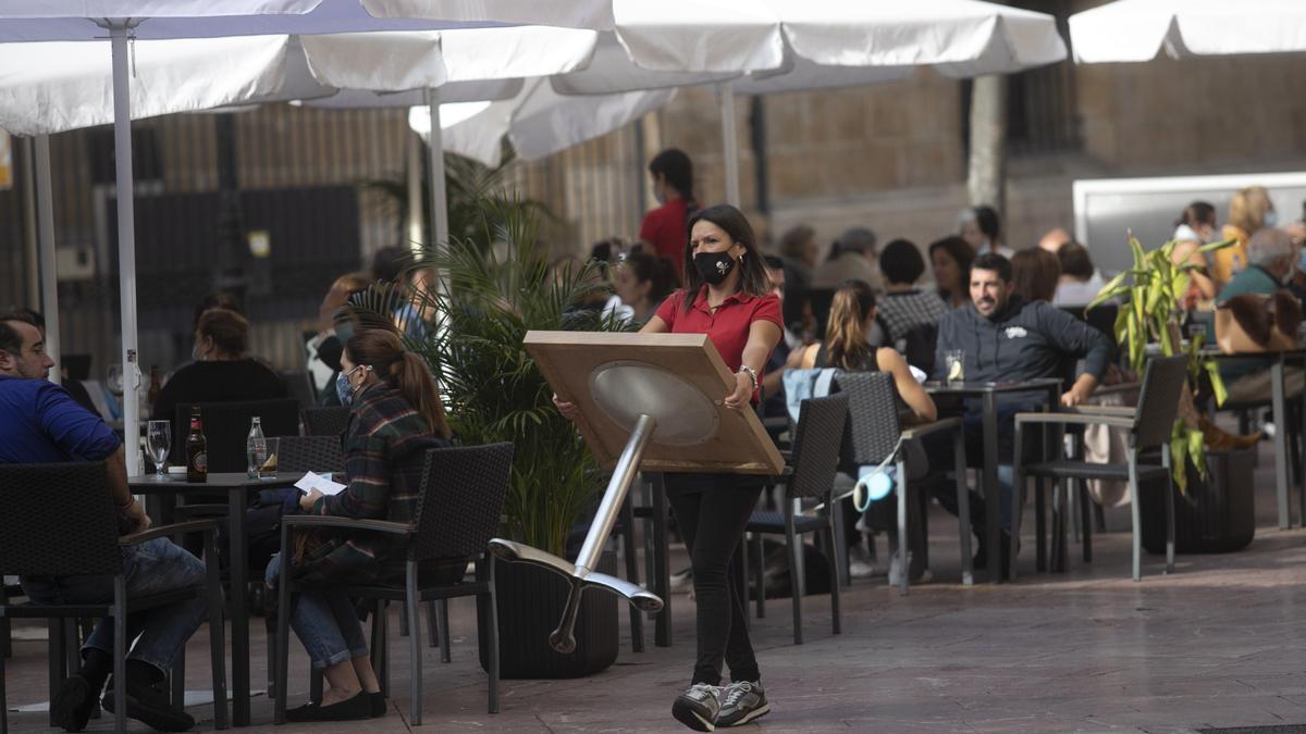 Una camarera asitia una mesa nuna terraza d&#039;Uviéu. | MIKI LÓPEZ