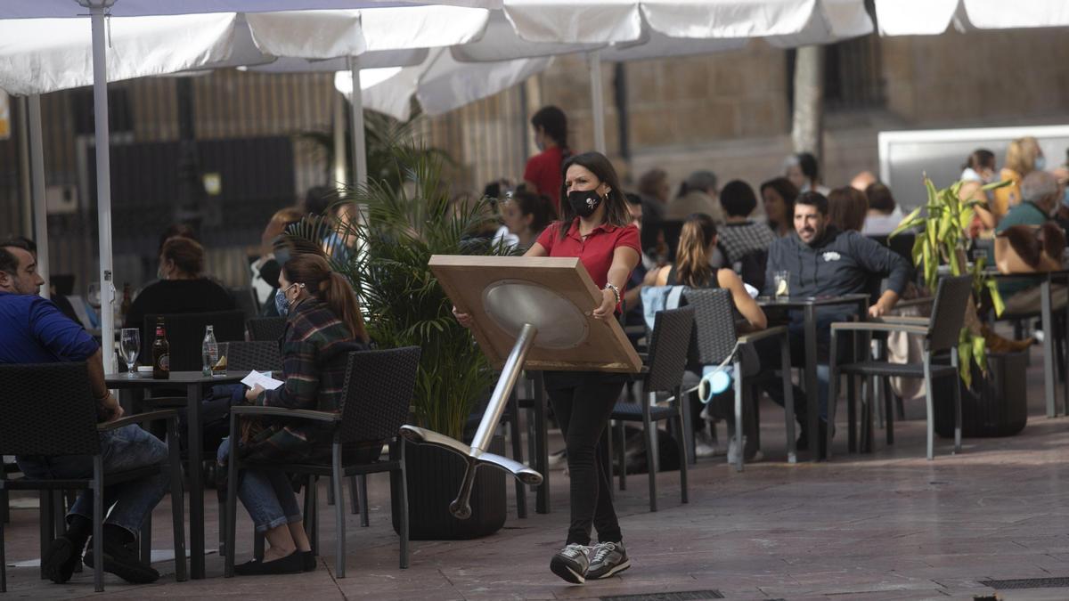 Una camarera coloca una mesa en una terraza de Oviedo. | MIKI LÓPEZ