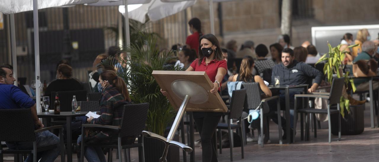 Una camarera coloca una mesa en una terraza de Oviedo. | MIKI LÓPEZ
