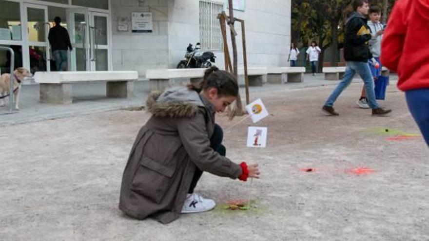 Una niña coloca una bandera tras pintar la caca con espray.