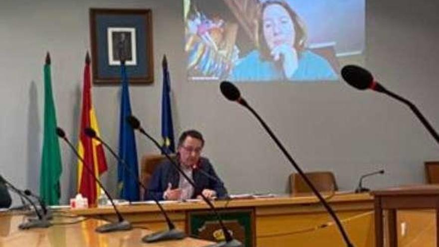 El concejal Javier González (PSOE), en el salón de plenos durante la comisión municipal, con la edil del PP Nuria González-Nuevo en la pantalla.