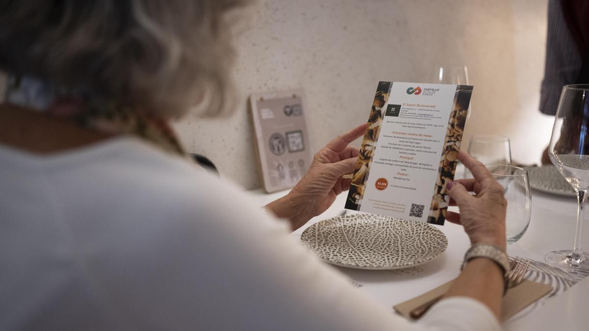 La clienta de un restaurante mira la carta Otoño Gastronómico Castelló Ruta de Sabor.