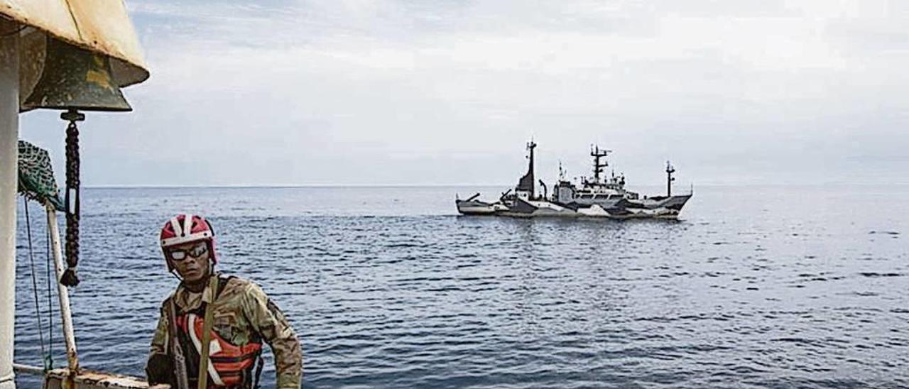 Un militar de Liberia, a bordo de un pesquero con la patrullera de Sea Shepherd al fondo. // Sea Shepherd