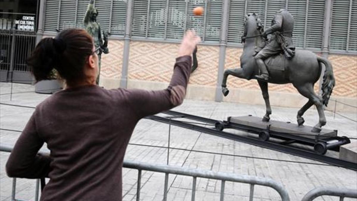 HUEVOS Una mujer prueba su puntería con la estatua de Franco.