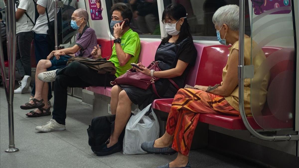 Pasajeros del metro de Singapur viajan protegidos con máscaras y respetando la distancia de seguridad.