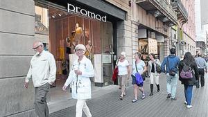 Unos transeúntes pasan ante comercios de la calle de Pelai.