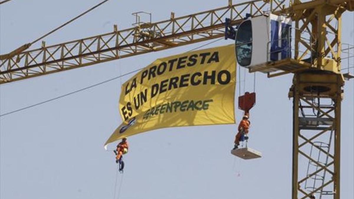 Activistas de Greenpeace despliegan una pancarta contra la 'ley mordaza' desde una grúa, en el Congreso.