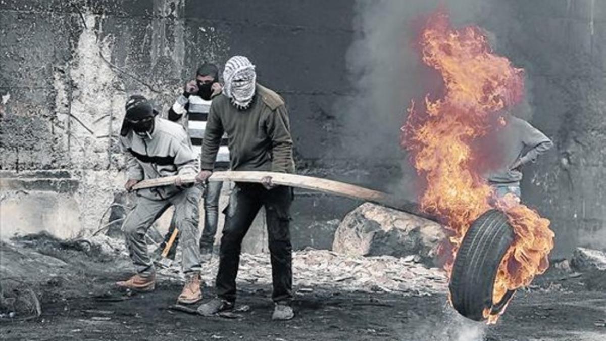 Manifestantes palestinos queman un neumático frente al muro, este lunes.