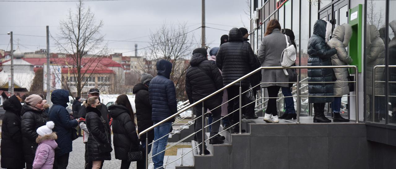 Ciudadanos ucranianos haciendo fila para sacar dinero de un banco.