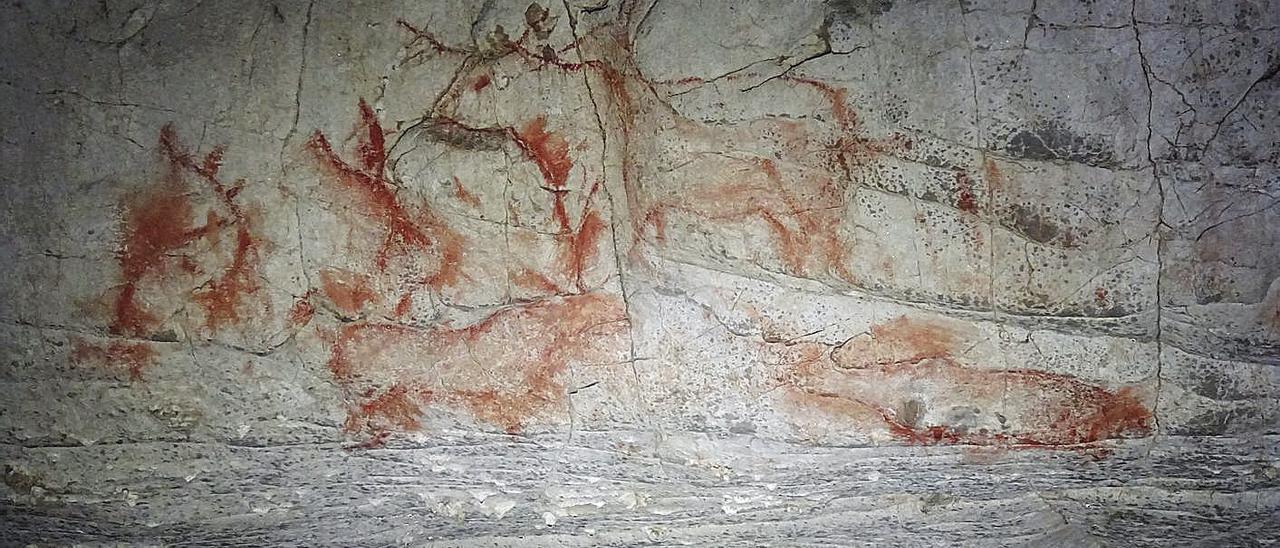 Uno de los conjuntos de pinturas de la cueva de Cobijeru, en color rojo, que representan figuras humanas y animales.