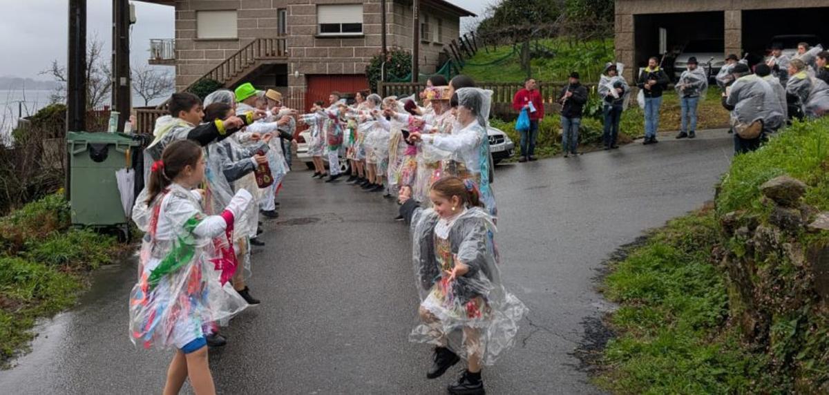 Baile con los disfraces tradicionales de Vilaboa bajo chubasqueros. | FDV