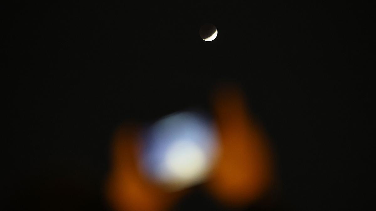 Una persona hace una foto con el móvil durante el eclipse lunar, en Pekín, China.