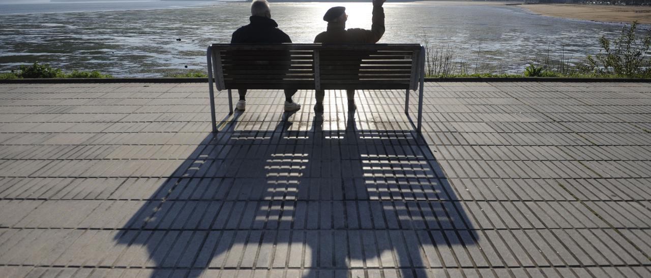 Dos pensionistas descansan en un banco frente al mar