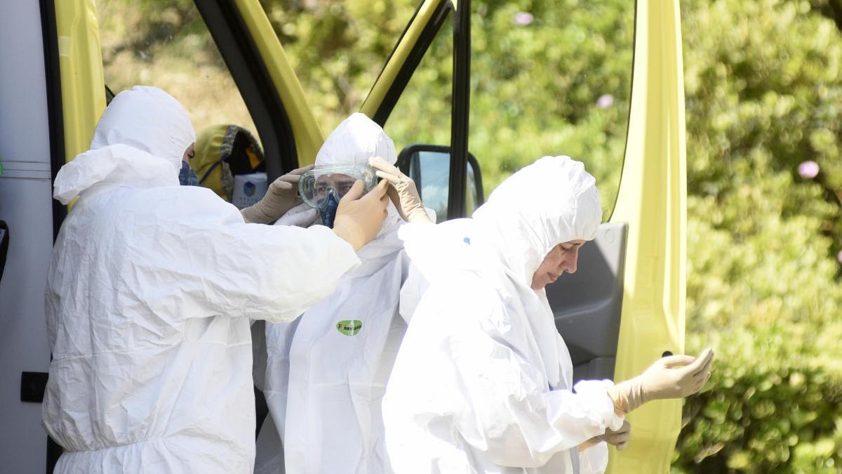 Profesionales del 061 se colocan los trajes EPI al bajar de la ambulancia.