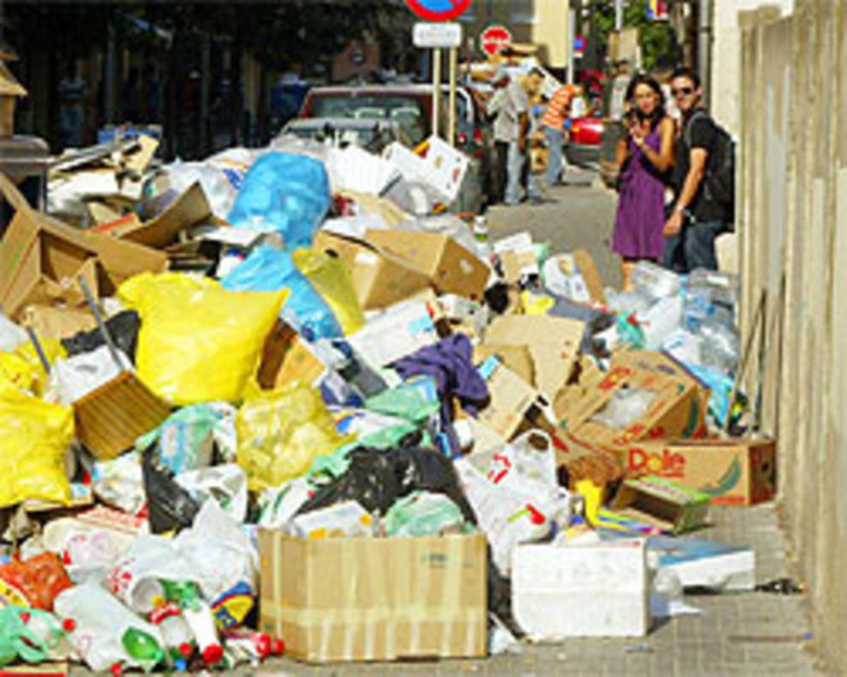 Uns ciutadans observen les escombraries acumulades en un carrer de Salt.