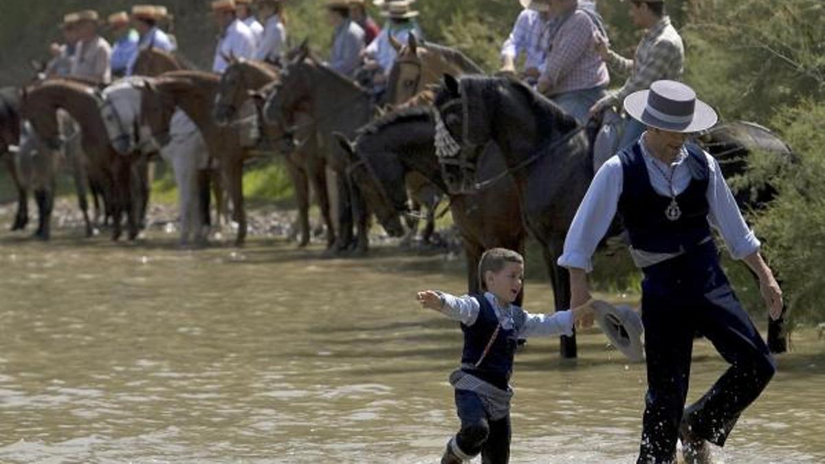 Peregrinos a pie y a caballo transitan el vado del río Quema camino a la aldea del Rocío.