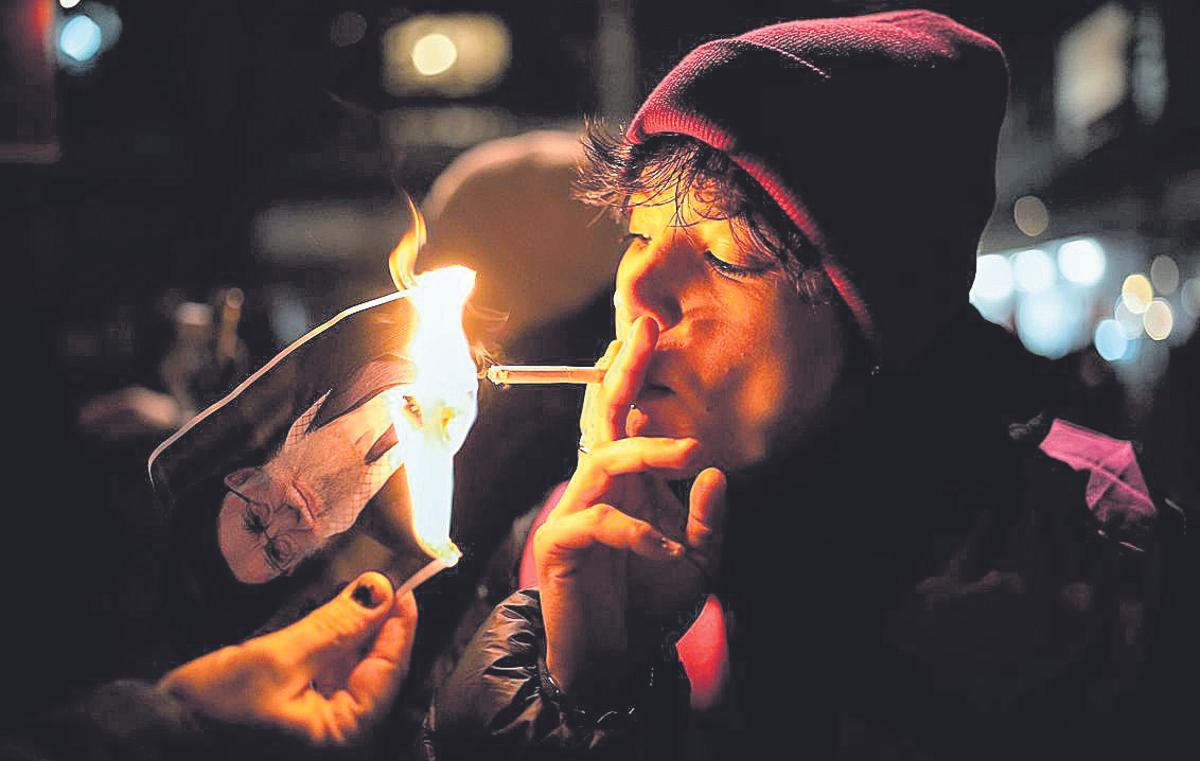 Un manifestante se enciende un cigarro con una foto de Alí Jamenei, el miércoles en Berlín.
