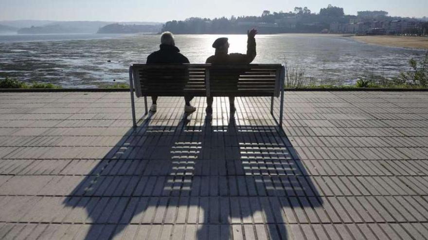 Dos jubilados observan el mar en un puerto gallego.