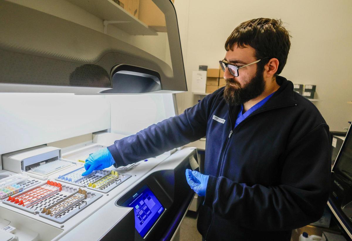 Un técnico introduce muestras para la secuenciación del genoma en el hospital Clínico.