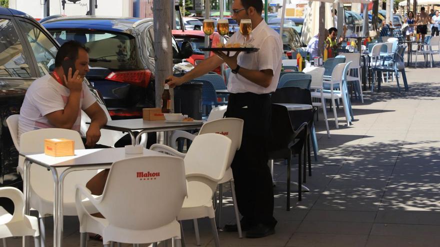 Un camarero sirve al cliente de una terraza de la playa de Gandia. | XIMO FERRI