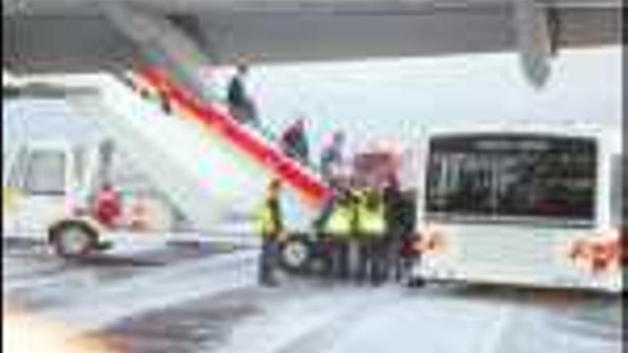 Pasajeros abandonan el avión nada más aterrizar en la pista de Lavacolla, cubierta de espuma para evitar un posible incendio del aparato. / xaime regueiro