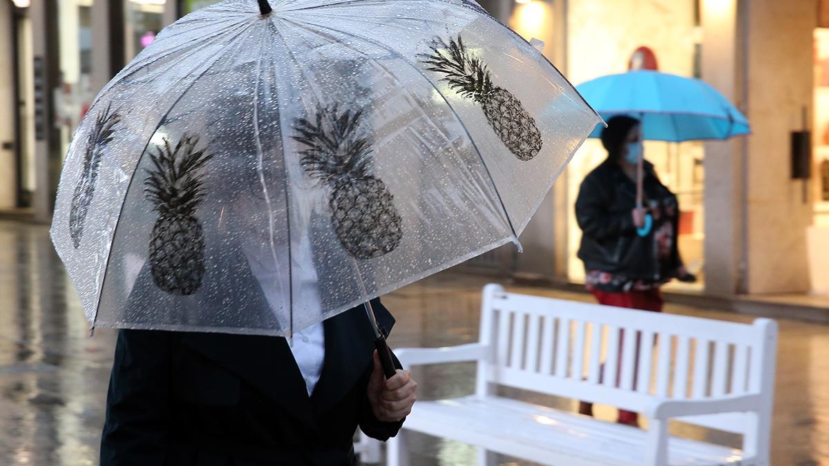 Una mujer se protege de la lluvia, esta tarde, en el centro de Vigo