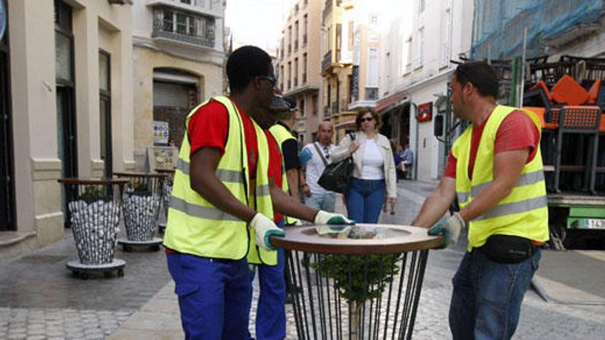 Dos operarios retiran una de las mesas de un comercio de Calle Granada.