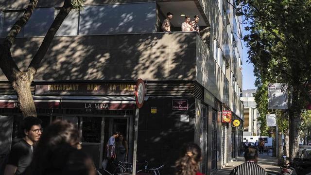 Turistes allotjats en un pis turístic observen i es dirigeixen a veïns concentrats contra els desnonaments al barri de la Mina. | ZOWY VOETEN