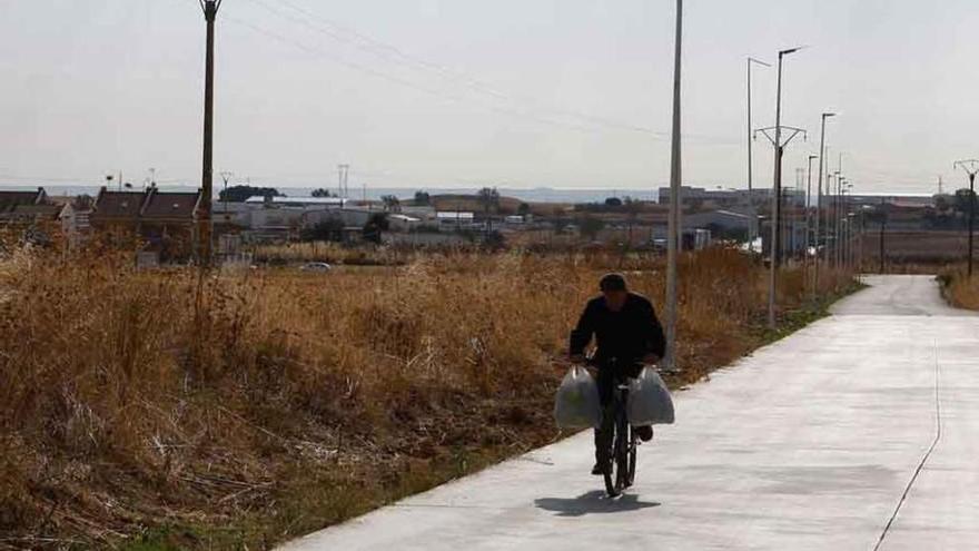 Una persona marcha en bicicleta por uno de los caminos de Roales. A la derecha, plano de los sectores industriales calificados como rústicos.