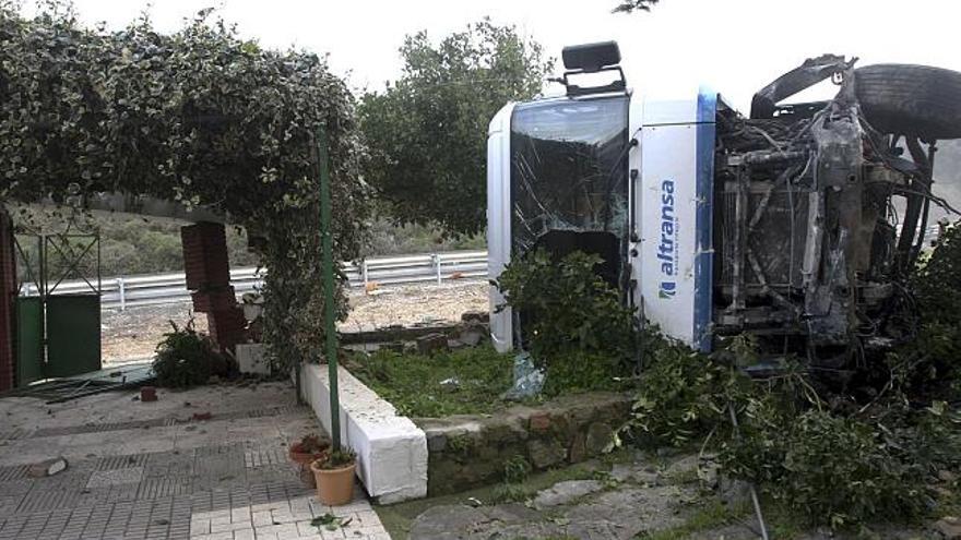 El camión tras colisionar contra el muro y porche de una vivienda cercana al lugar del accidente, después de chocar contra el turismo.