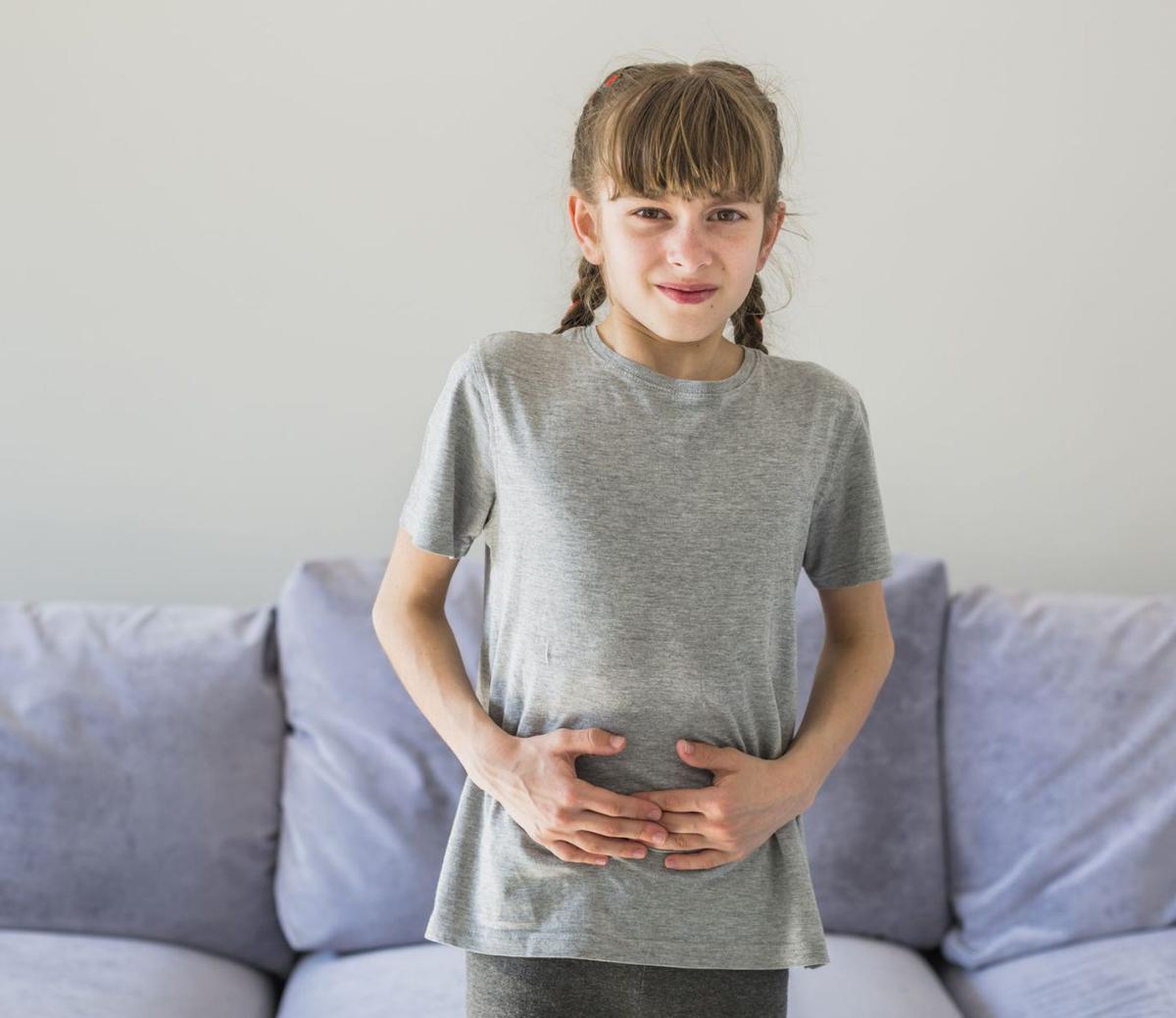 Una niña se lleva las manos al estómago.