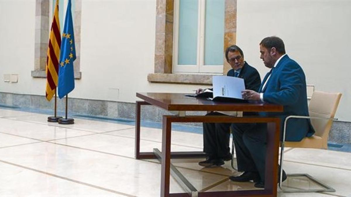 El presidente de la Generalitat, Artur Mas, y el presidente de ERC, Oriol Junqueras, durante el acto de firma del pacto de gobernabilidad, el pasado 19 de diciembre en el Parlament.