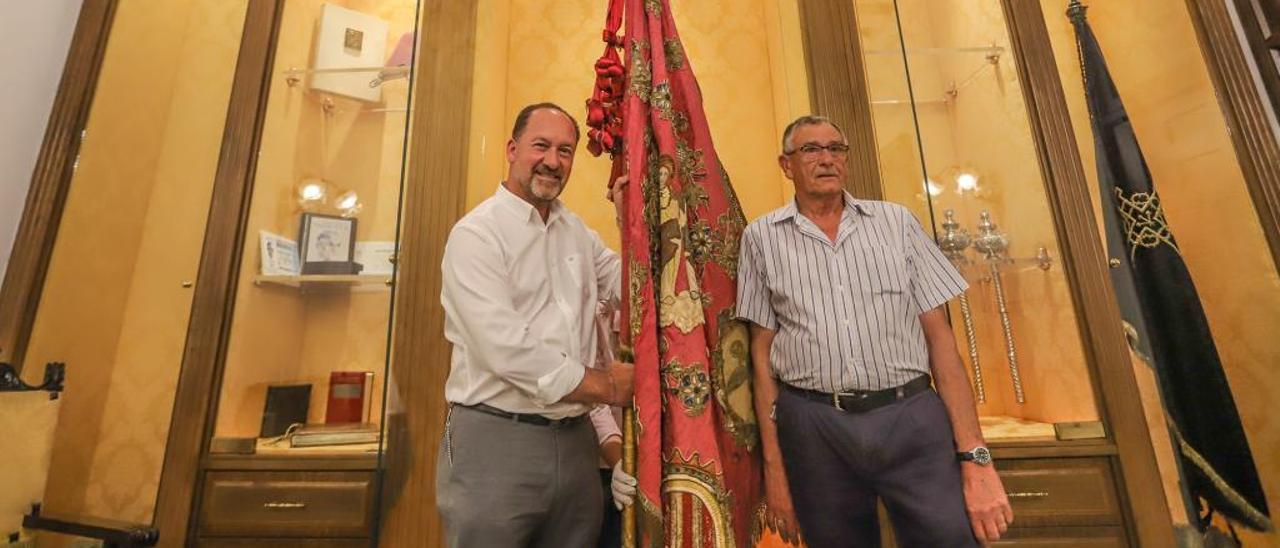 Marcelino Asuar y el alcalde oriolano, Emilio Bascuñana, flanquean la Gloriosa Enseña del Oriol, ayer, en la sala del Ayuntamiento donde se custodia todo el año.