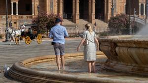 Turistas se refrescan en la fuente de la Plaza de España en Sevilla, en imagen de archivo.