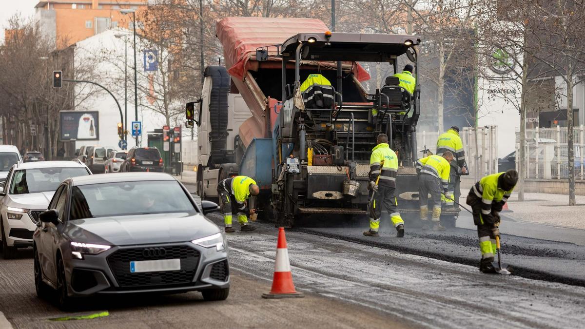 Unos trabajadores junto a una máquina asfaltando en Zaragoza