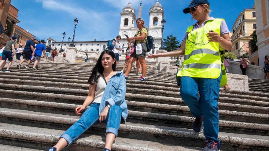 Una vigilante advierte a una turista de la prohibición de sentarse en la escalinata de la plaza de España en Roma.