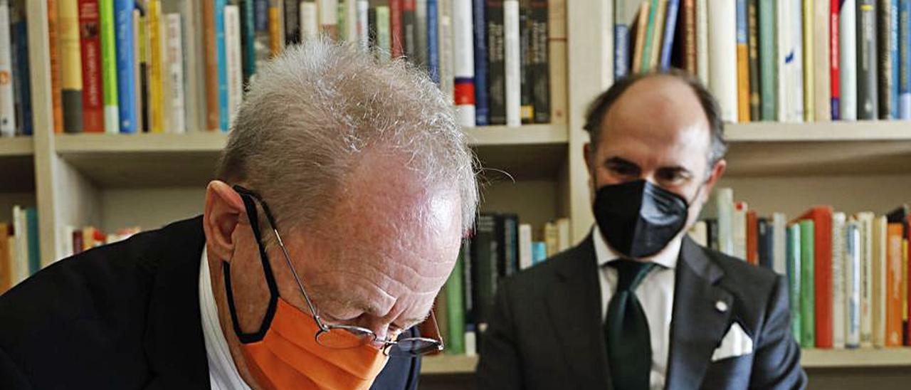 Geoffrey Hewings, firmando una dedicatoria, ayer, tras su donación, con el rector, Ignacio Villaverde, al fondo. | Luisma Murias