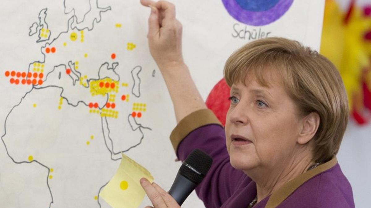 La cancillera Merkel señala en un mapa la procedencia de los alumnos de un colegio de Berlín.