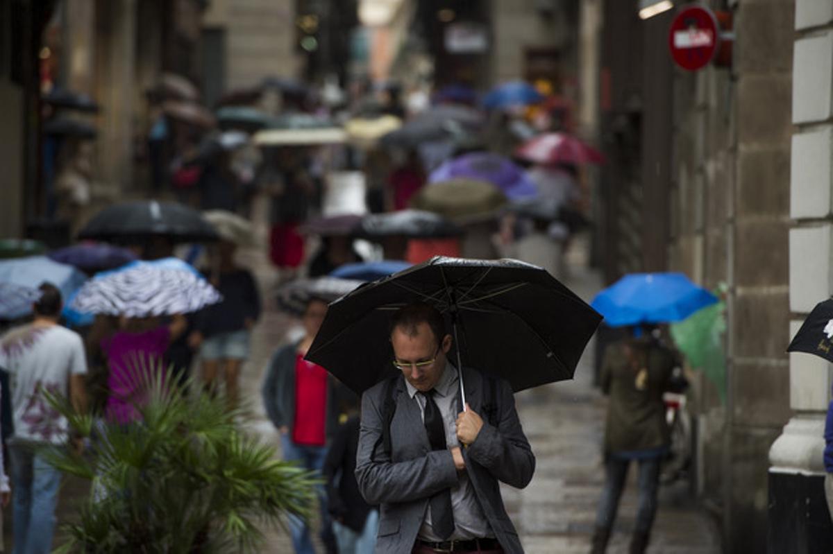 Viandantes se protegen de la lluvia con paraguas por las calles del barrio Gòtic, en una imagen de archivo.