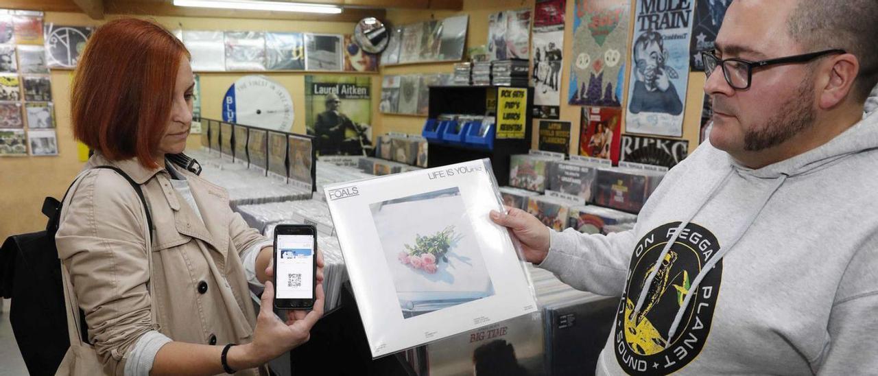 Una clienta mostrando ayer el código QR del bono en la tienda de discos Honky Tonk.