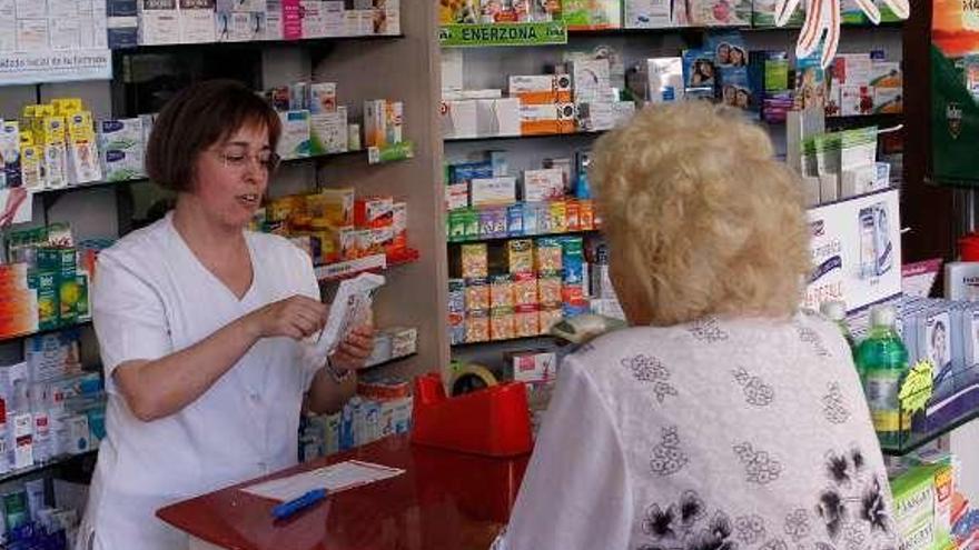 Una señora es atendida en el interior de una farmacia.