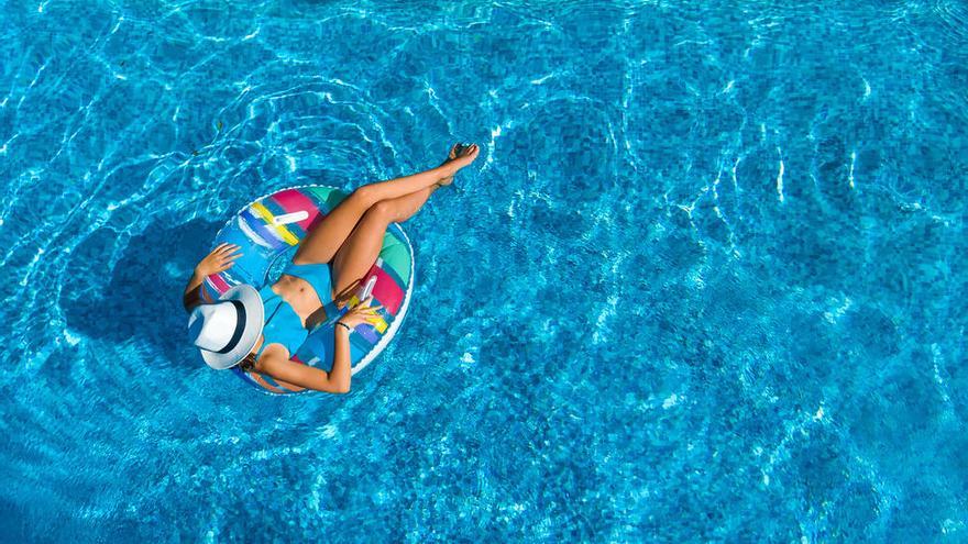 Una mujer se baña en una piscina encima de un flotador.