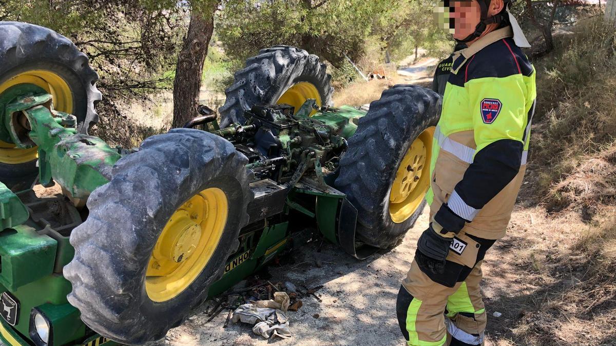 Un bomberos del CEIS al lado del tractor volcado.