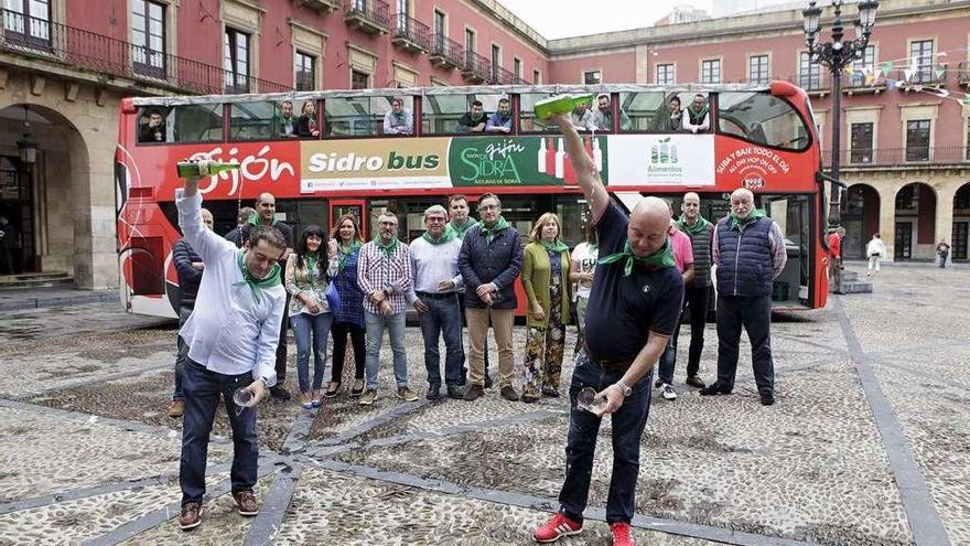 Dos escanciadores sirven un culín de sidra ante el &quot;Sidrobús&quot;, aparcado en la plaza Mayor.