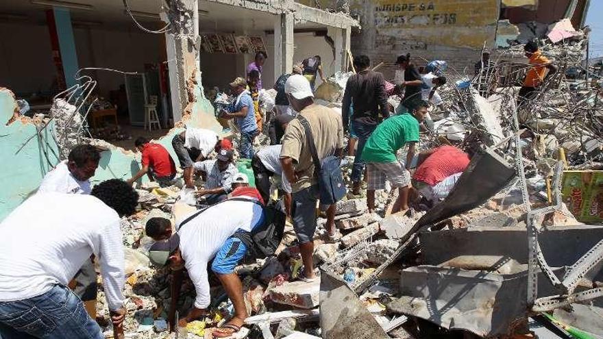 Ecuatorianos buscan comida y enseres entre los escombros. // Efe