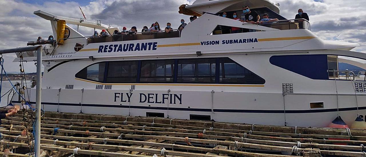 El “Fly Delfín”, abarloado a una batea para mostrar el cultivo de mejillón.